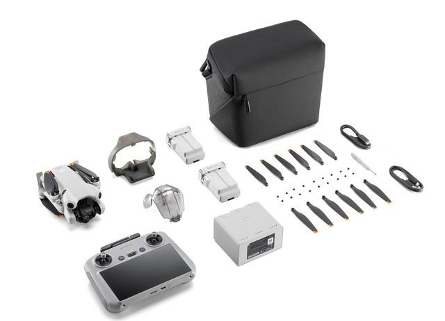 Drone kit with controller, spare propellers, and carrying case laid out on a white background.